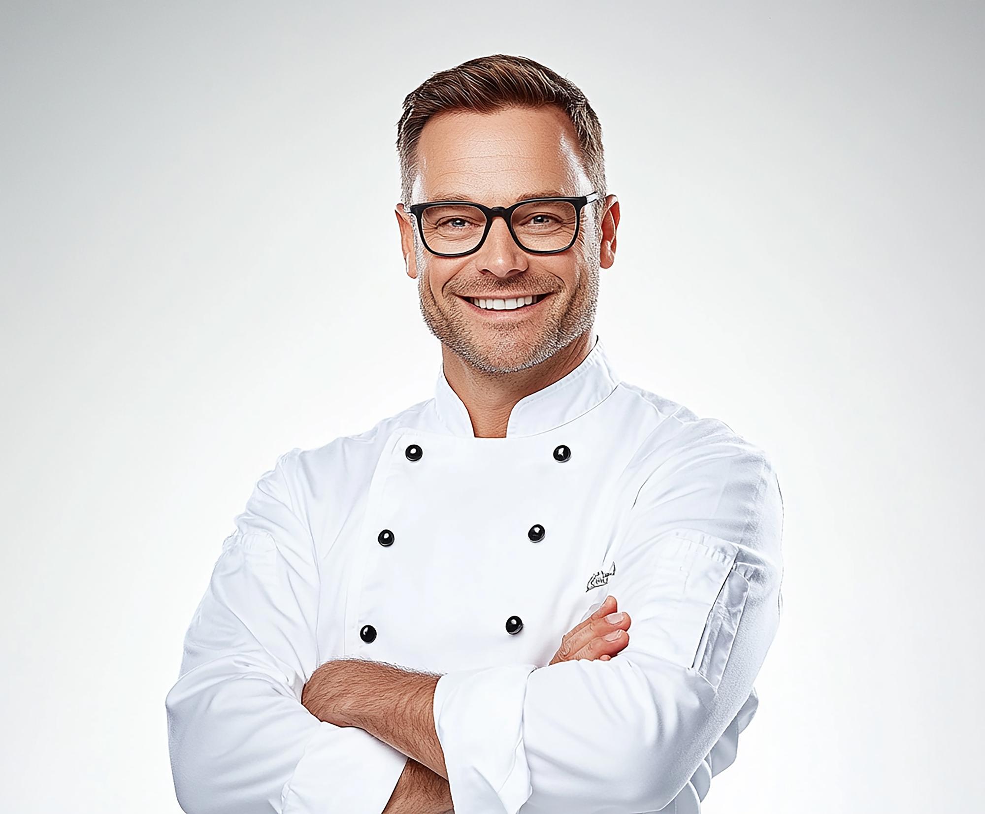 Lead chef smiling, wearing a modern apron